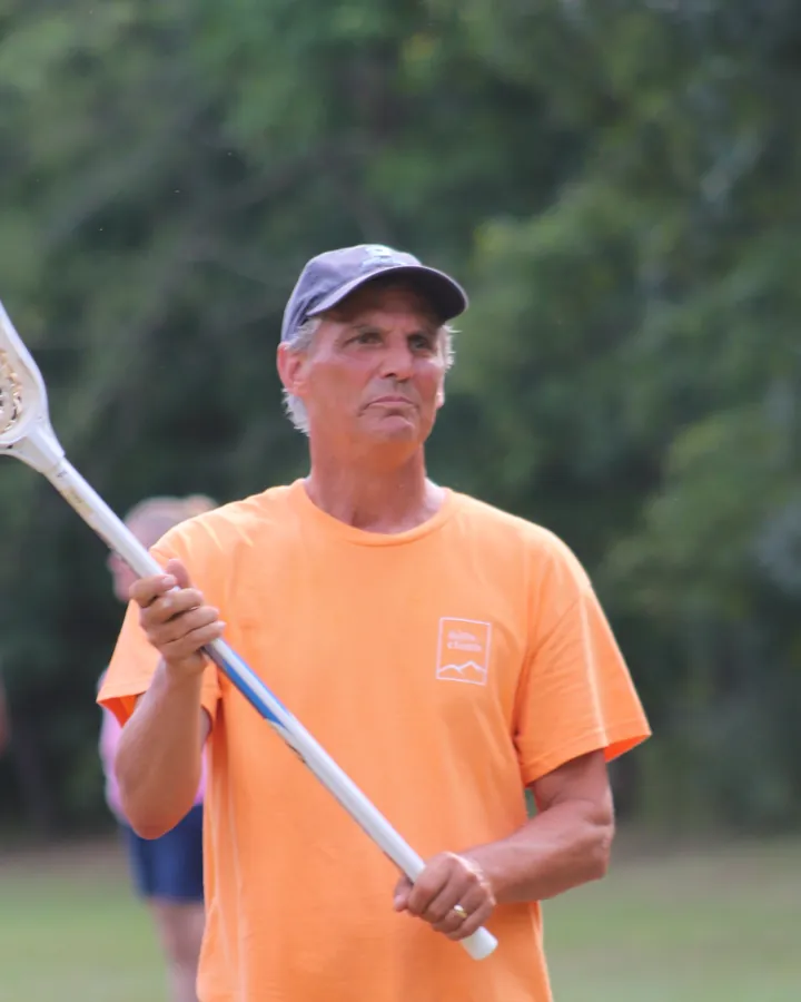 Robert Smith holding a lacrosse stick on the camp field